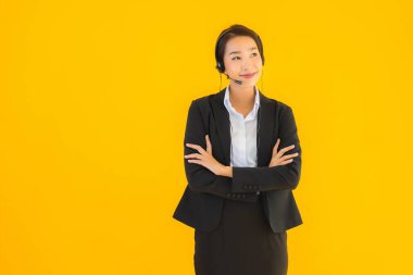 Portre güzel genç Asyalı kadın kulaklık ya da çağrı merkezi için kulaklık ya da tele pazarlama sarı izole arka planda.