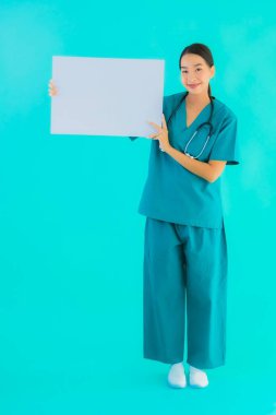 Fotokopi için boş kâğıt tahtası olan güzel Asyalı genç doktor kadın hastane ve klinikteki sağlık hizmetleri konseptinde mavi izole edilmiş arka plan.