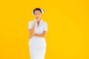 Güzel Asyalı genç Taylandlı hemşirenin portresi klinikteki ve hastanedeki hastalar için sarı izole edilmiş arka planda birçok eylem çalışmasında yer alıyor.