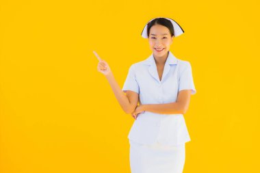 Güzel Asyalı genç Taylandlı hemşirenin portresi klinikteki ve hastanedeki hastalar için sarı izole edilmiş arka planda birçok eylem çalışmasında yer alıyor.
