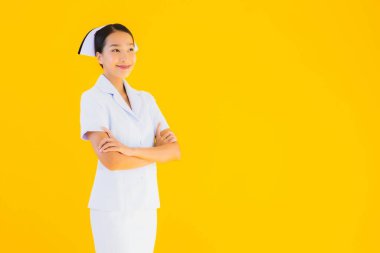 Güzel Asyalı genç Taylandlı hemşirenin portresi klinikteki ve hastanedeki hastalar için sarı izole edilmiş arka planda birçok eylem çalışmasında yer alıyor.
