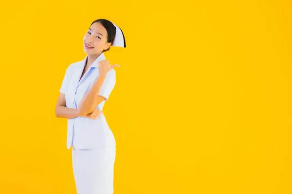 肖像画黄色の隔離された背景にクリニックや病院での患者のための多くのアクションの仕事で美しい若いアジアのタイの看護師 — ストック写真