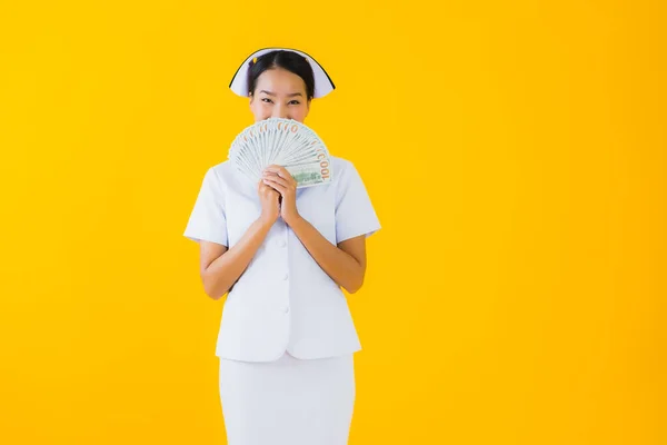ポートレート美しいです若いですアジアの女性タイ看護師とともに多くの現金とお金とピンクの貯金箱上の黄色隔離された背景 — ストック写真
