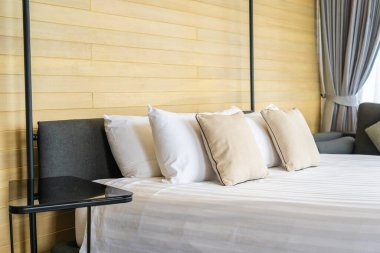 Otel odasındaki yatak odasının iç dekorasyonunda beyaz rahat yastık.