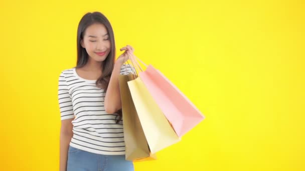 美丽的亚洲女人拿着用黄色隔开的彩色纸袋的镜头 — 图库视频影像