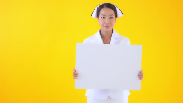 Footage Beautiful Asian Nurse Holding Blank Board Isolated Yellow — Stock Video
