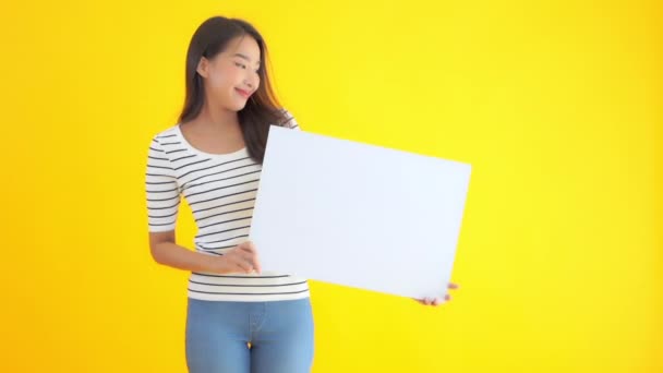 Πλάνα Από Όμορφη Ασιάτισσα Γυναίκα Κρατώντας Λευκό Πίνακα Απομονώνονται Κίτρινο — Αρχείο Βίντεο