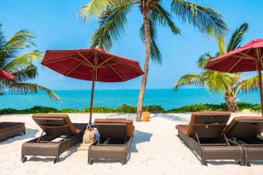 Güzel tropikal deniz okyanusu, şemsiyesi ve sandalyesi ile mavi gökyüzünde hindistan cevizi palmiyesinin etrafında tatil için