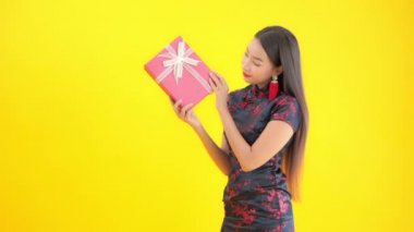 Sarıya izole edilmiş kırmızı hediye kutusu taşıyan geleneksel giysili güzel Asyalı kadının görüntüleri.