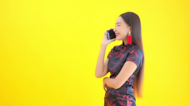 黄色で隔絶された電話で話す伝統的なドレス姿の美しいアジア人女性の映像 — ストック動画