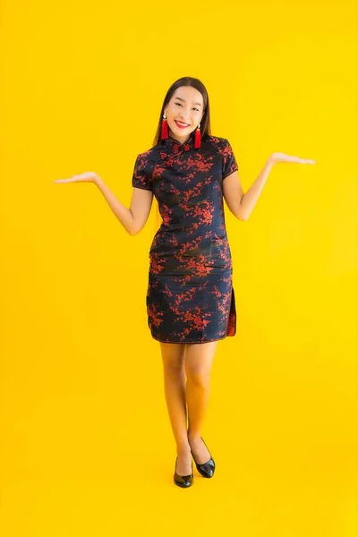 肖像美しい若いアジアの女性は黄色の孤立した背景に中国の新年のコンセプトのためのアクションと中国のドレスを身に着けている — ストック写真