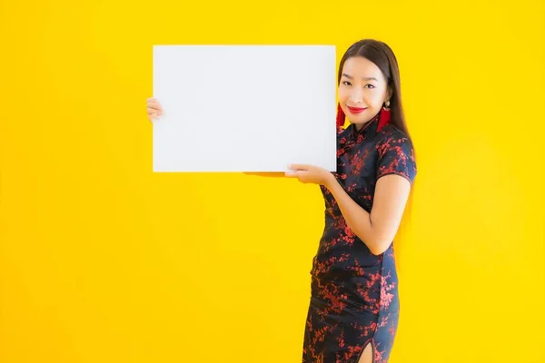 穿着中国服装的美丽的亚洲年轻女子形象在中国新年的概念中 在黄色孤立的背景下 展示了白纸空白字的广告牌 — 图库照片