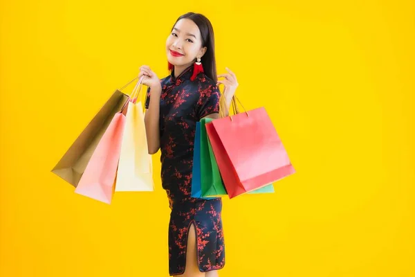 肖像画美しい若いアジアの女性は中国のドレスでショッピングバッグ スマートフォン クレジットカードで中国の旧正月に黄色の隔離された背景 — ストック写真