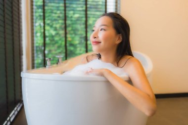 Güzel bir Asyalı kadın portresi mutlu bir gülümseme rahatla banyo küvetinde banyo yap.