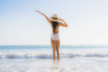 Güzel bir Asyalı kadın portresi. Okyanus sahillerinde mutlu bir gülümseme ve tatil için mavi bir gökyüzü.