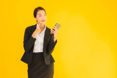 Portre güzel genç Asyalı kadın akıllı cep telefonu ve kahve fincanı ile izole edilmiş sarı arka planda