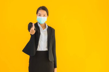 Güzel genç iş kadını portresi Korunmak için maske takıyor 19 koronavirüs sarı izole arka planda