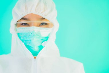 Güzel, genç Asyalı doktor kadın portre. Koronavirüsten ya da mavi arka planda kovid19 'dan korunmak için ppe ya da kişisel koruyucu ekipman takıyor.