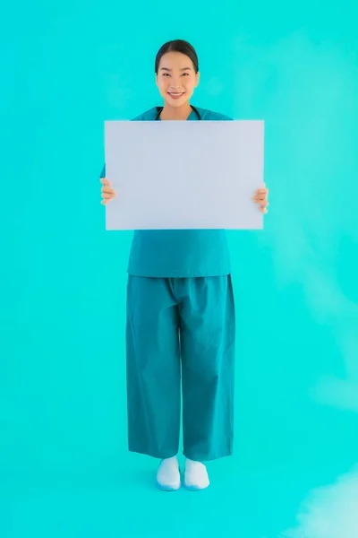 青い隔離された背景にコピースペースのための空の紙板紙と肖像画の美しい若いアジアの医師の女性 病院やクリニックのコンセプトのヘルスケア — ストック写真