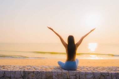 Genç Asyalı kadının portresi sağlık için gün doğumunda deniz kıyısı okyanusunda meditasyon yapıyor.