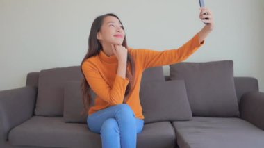 Evde akıllı telefon kullanan Asyalı güzel bir kadının görüntüleri.
