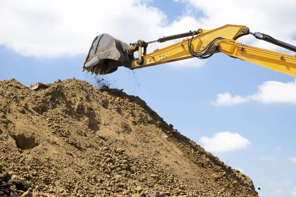 La excavadora amarilla carga el suelo en el sitio de construcción — Foto de Stock