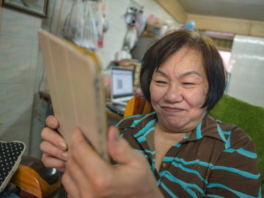 Evinde tablet öğrenen ve kullanan yaşlı Asyalı kadınların portresi, eğitim kavramı