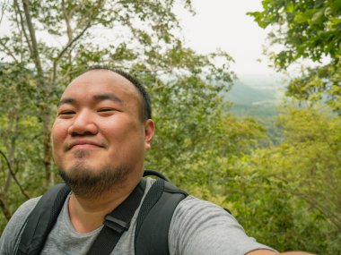 Tayland 'ın Sukhothai bölgesindeki Ramkhamhaeng Ulusal Parkı' ndaki Khao Luang Dağı 'nın zirvesine giden Asyalı turistin portre fotoğrafı.