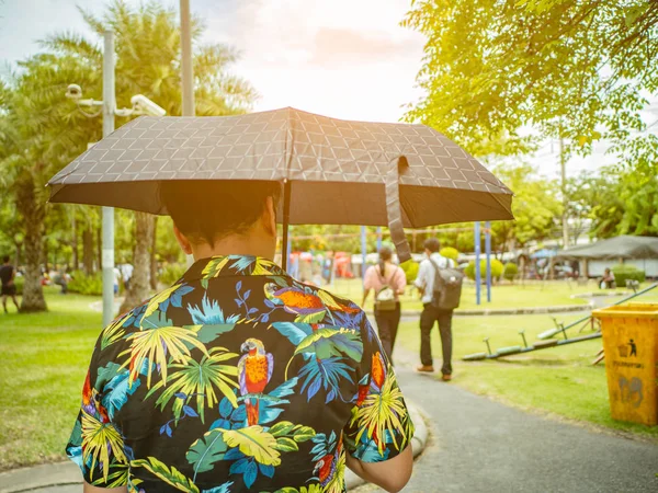 Красивый Азиатский Мужчина Носит Футболку Изображением Хавай Держа Зонтик Гуляя — стоковое фото