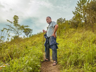 Tayland 'ın Sukhothai bölgesindeki Ramkhamhaeng Ulusal Parkı' nda Khao Luang dağında Asyalı Şişman bir gezgin yürüyüş yapıyor.