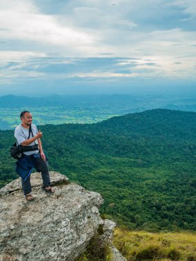 Asyalı Şişman Adam, Tayland 'ın Sukhothai bölgesindeki Ramkhamhaeng Ulusal Parkı' ndaki Khao Luang Dağı 'nda kayalık kayalıklarda duruyor.