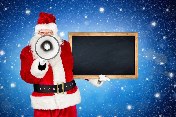 传统的经典红白圣诞老人做大声宣布与扩音器扩音器木黑板在他的另一只手在圣夜蓝色星空背景的前 — 图库照片