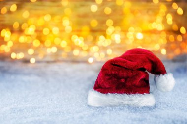 kırmızı beyaz Noel Baba Noel şapka parlak altın ışık bokeh arka plan önünde, karda