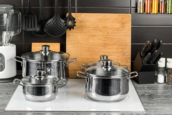 Cooking pots in kitchen on white induction hob — Stock Photo, Image