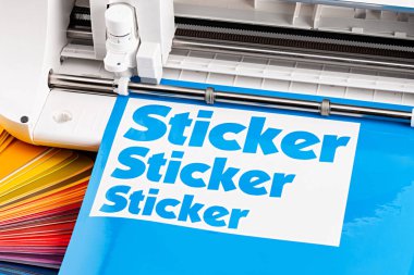 Renk yelpazeli mavi renkli vinil fim üzerindeki çizer kesme makinesiyle prodüksiyon çıkartması yapıyor. Rehber. Reklam endüstrisi diy tasarım kavramı arka planı.
