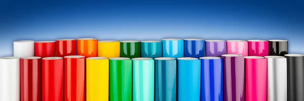 Çeşitli gökkuşağı renkli vinil araba ambalajı ya da çizicisi mavi beyaz panorama afiş arka planında folyo ruloları kesiyor