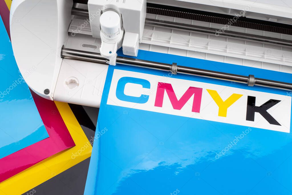 production making CMYK sticker with plotter cutting machine on cyan blue colored vinyl film Advertising Industry diy design on concept background.