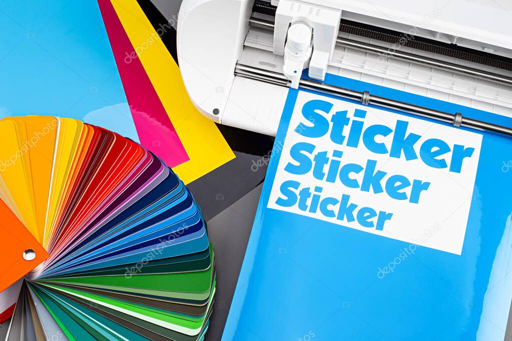 production making sticker with plotter cutting machine on CMYK cyan blue colored vinyl fim with color fan. guide. Advertising Industry diy design concept background.