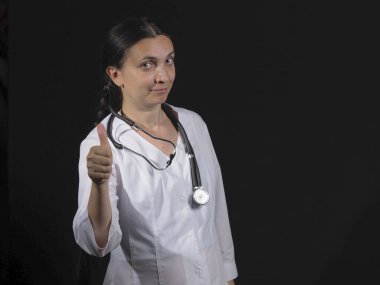 Kadın doktor el hareketlerini ve siyah arka planda poz veriyor.