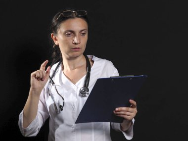 Kadın doktor siyah arka planda duygu gösteriyor.