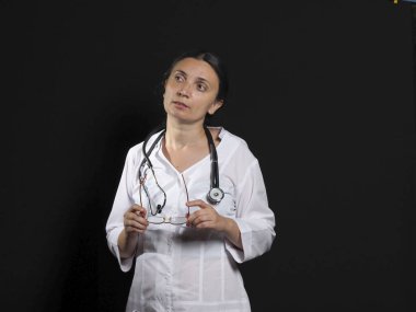 Kadın doktor el hareketlerini ve siyah arka planda poz veriyor.