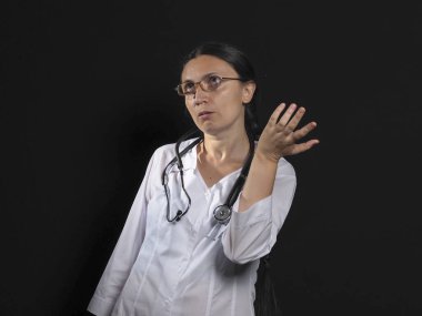 Kadın doktor el hareketlerini ve siyah arka planda poz veriyor.