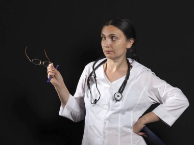 Kadın doktor el hareketlerini ve siyah arka planda poz veriyor.