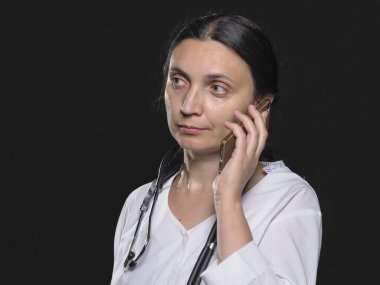 Kadın doktor telefonla poz verirken farklı duygular gösteriyor