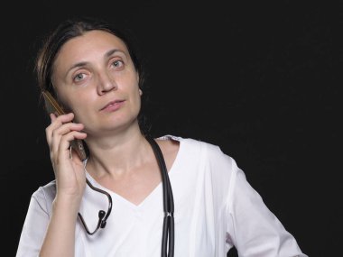 Kadın doktor telefonla poz verirken farklı duygular gösteriyor