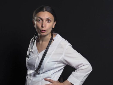 Kadın doktor el hareketlerini ve siyah arka planda poz veriyor.