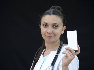 Avrupalı kadın doktor elinde bir kutu ilaç tutuyor.