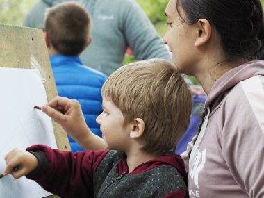 Anne ve çocuk bir kalemle çiziyor.