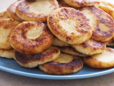 Altın kabuklu lezzetli peynirli kekler bir tabakta yığılır.