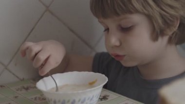 Küçük bir çocuk masada yemek yiyor.